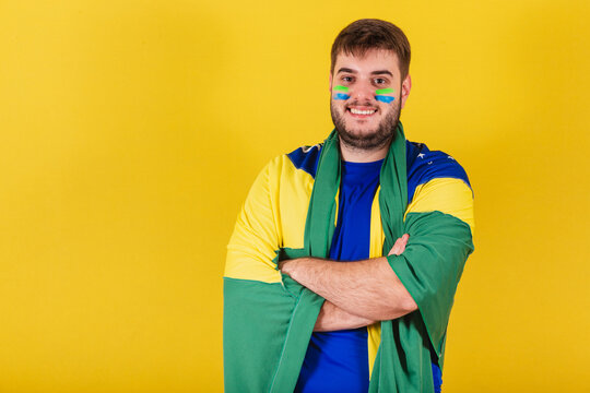 caucasian brazilian man, brazil soccer fan, arms crossed, wearing brazil flag cape.