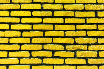 Yellow paint brick wall. Abstract color home facade background. Decorative artistic urban construction. Grunge color street design texture. Bright vibrant wall pattern.