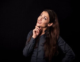 Beautiful thinking toothy smiling business woman with folded arms looking up in blue shirt on black background with empty copy space for text. Closeup