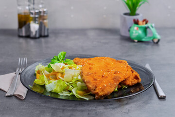 Fried Chicken Breast with Sesame Seeds on a Bed of Fresh Salad in the hotel 