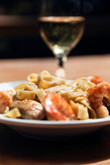 Pasta with shrimp in an Italian restaurant. Accompanied by a glass of white wine.