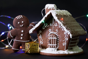 Gingerbread house, gingerbread man, gift and colorful lights on a dark background. Element of...