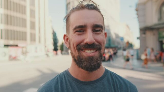 Portrait of young smiling man with beard standing in front of busy intersection