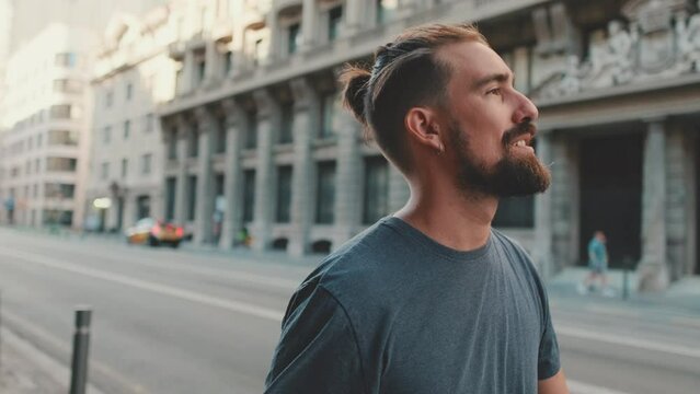 Profile of young smiling man with beard walking down the street