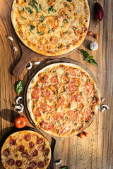 Three pizzas of different flavors. Pepperoni, cheese, potato, onion, tomato. Italian pizza.