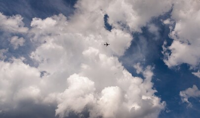 The plane in the sky is flying under the clouds