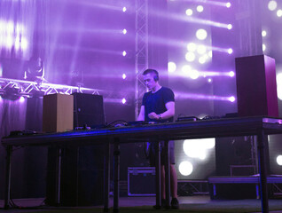 Dj playing techno music on the stage at night summer concert