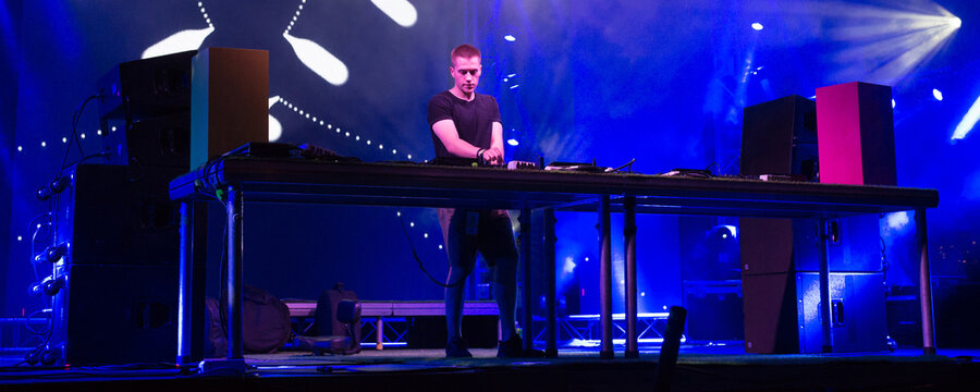 Dj playing techno music on the stage at night summer concert