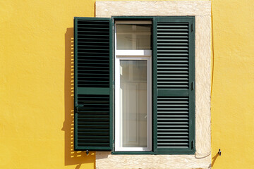 Traditional and vintage Portuguese house style, Green wooden louver window and yellow concrete concrete wall, Lisbon is capital city of Portugal.