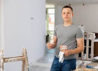 Portrait of teenage boy holding bunch of earned money for part-time work in construction site.