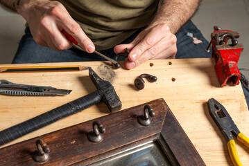 man's hands restoring a small piece of metal from a piece of furniture, 

