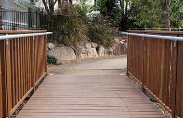 Bridge in a park leading to a path surrounded by rocks and plants