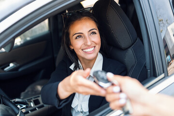 Car rental agency employee giving car keys to beautiful young woman.