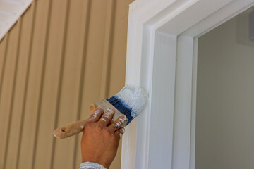 The carpenter applies paintbrush to wooden moldings door trim for the purpose of painting them
