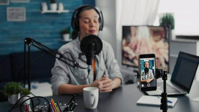 Social media influencer using modern laptop while streaming remote podcast show on smartphone. Creative digital content creator recording daily vlog with modern touchscreen cellphone device.