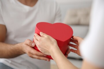 Man presenting gift to his beloved woman at home, closeup. Valentine's day celebration