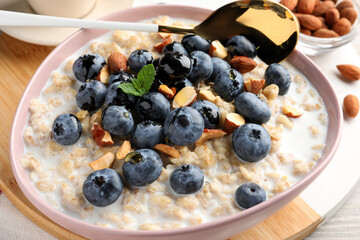 Tasty oatmeal porridge and ingredients served on table, closeup. Healthy meal