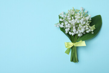 Beautiful lily of the valley flowers on light blue background, top view. Space for text