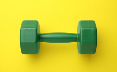 Stylish dumbbell on yellow background, top view
