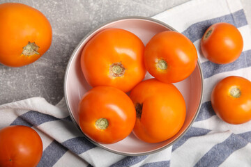 Many ripe yellow tomatoes on grey table, flat lay