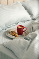 Obraz na płótnie Canvas Cup of aromatic coffee and cookies on bed with soft blanket
