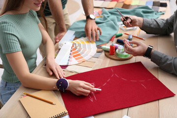 Fashion designers creating new clothes at table in studio, closeup