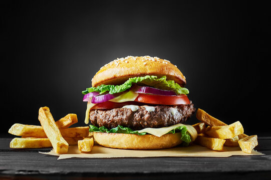Craft Beef Burger And French Fries On Wooden Table Isolated On Black Background.
