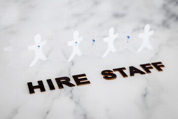 Hire Staff text with paper people chain and question marks on vacant positions to fill, staff...