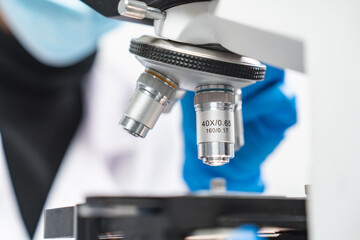 professional research scientist using microscope in science chemistry laboratory, medical technology for biology or microbiology medicine discovery, scientific equipment for experiment in hospital lab