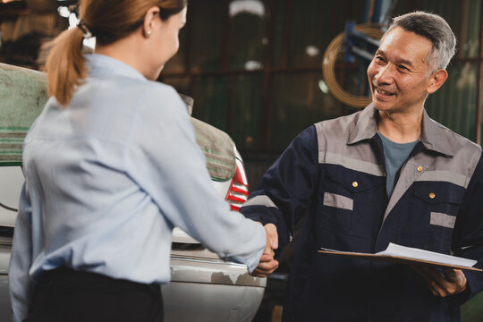 Mechanic technician man shaking hands with customer after finish checking the car at the garage, two people handshake for a working job at professional auto car repair service center