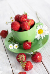 ripe strawberries from the garden in a green mug with white chamomile, summer 