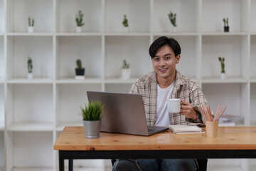 Asian man using laptop computer working at office. Creative and new idea concpet