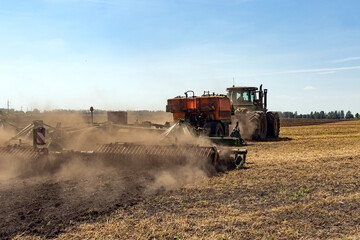 Naklejka premium The tractor plows the land. Agriculture image.