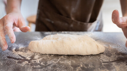 Obraz premium The process of making traditional French baguettes. Forming a blank from the dough. Front view.