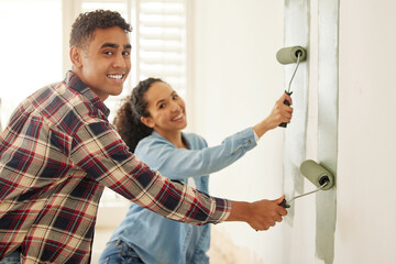 Happy couple painting for renovation with a brush in the living room at home. Portrait of a...