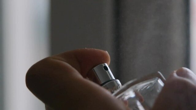 slow motion video, pressing of perfume button, spraying and spread of perfume at air.