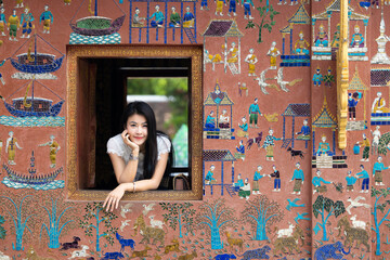 Asian woman tourist traveler at window Wat Xieng Thong temple in Luang Prabang, Laos, Wat Xieng Thong in Luang Prabang, Laos, UNESCO Town Luang Prabang World Heritage Site Wat Xieng Thong temple.