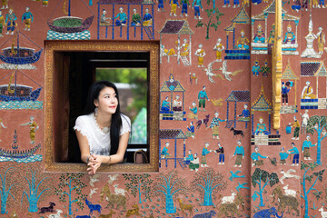 Asian woman tourist traveler at window Wat Xieng Thong temple in Luang Prabang, Laos, Wat Xieng Thong in Luang Prabang, Laos, UNESCO Town Luang Prabang World Heritage Site Wat Xieng Thong temple.