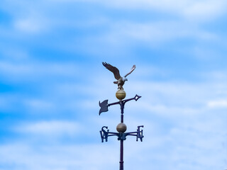 Weather-vane against sky comprising eagle,pointer and points of compass