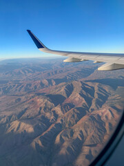 view from airplane window flying over rocky mountains