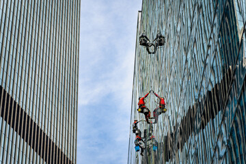 Industrial climbers cleaning windows on the facade of an office building.