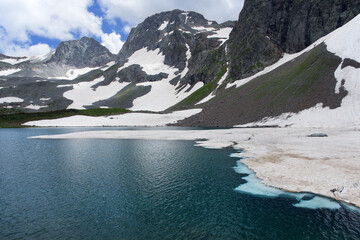 Obraz premium Shooting with focus stick. Mountain lake with ice floes floating in it. Mountain peaks in the background.