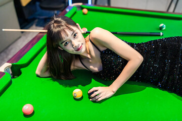 A sexy woman in a black halter dress at a pool table