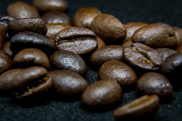 The way coffee beans lay on a black background, elegant and delicious coffee beans and the aroma of morning coffee.