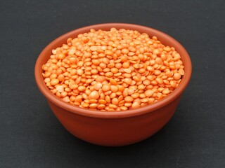 Red lentils in a bowl on black background 