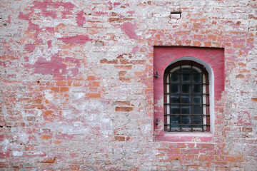Brick old wall with a window with bars