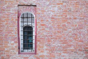 Fototapeta na wymiar Old rough brick wall with concrete and with window with bars