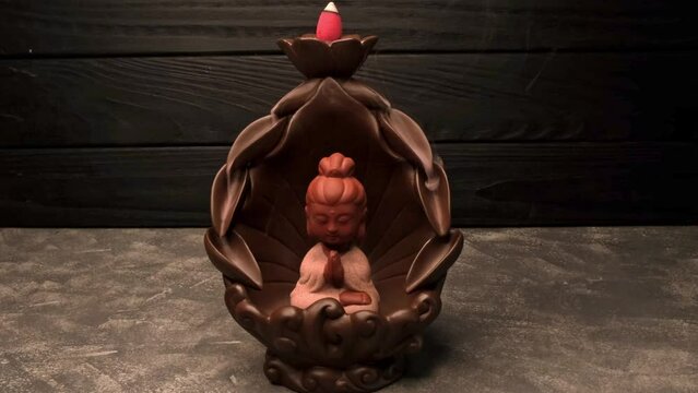 Buddha figurine with incense smoke. Aromatherapy and spa. Religious concept. Herbal medicine. Ceremony of worship of the Buddha. Indian religious symbol. Calming zen interiors with buddha statue.