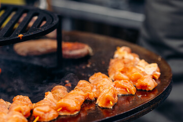 Cook grills kebab chicken open fire. Turns meat over with tongs. Concept Street food