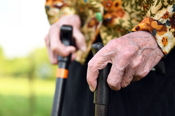 Elderly woman of 90 years put her hands on a cane, retirement and disability, close up.Elderly people are susceptible to the virus, coronavirus.	